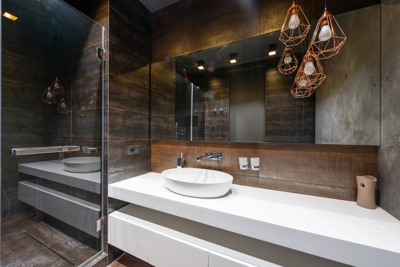 About A sleek modern bathroom featuring pendant lighting and a contemporary sink.